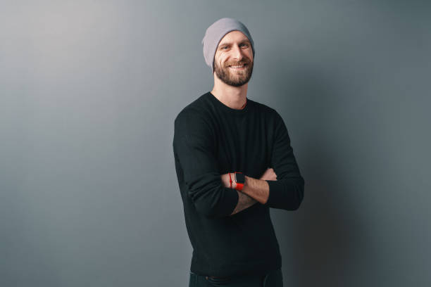 istock Young smiling man with beard and glasses, standing crossed arms on a gray studio background 1158169398
