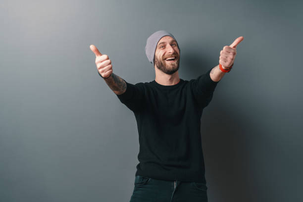 istock Happy smiling man holding thumbs up on gray background. 1158169412