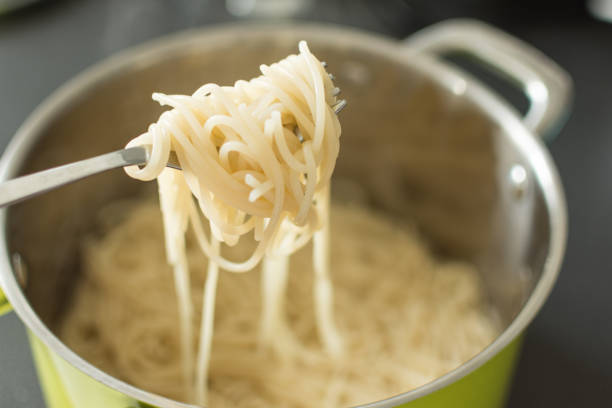 istock Boiled spaghetti hanging from a fork in the pan background. 1158171643