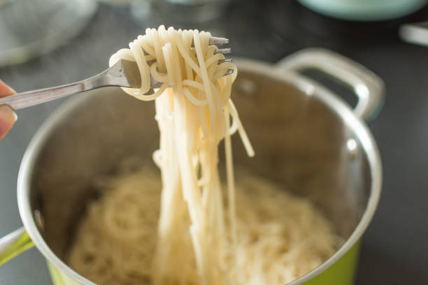 istock Boiled spaghetti hanging from a fork in the pan background. 1158171725