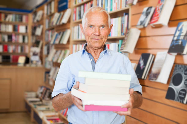 istock Elderly man holding books in bookstore 1158172468