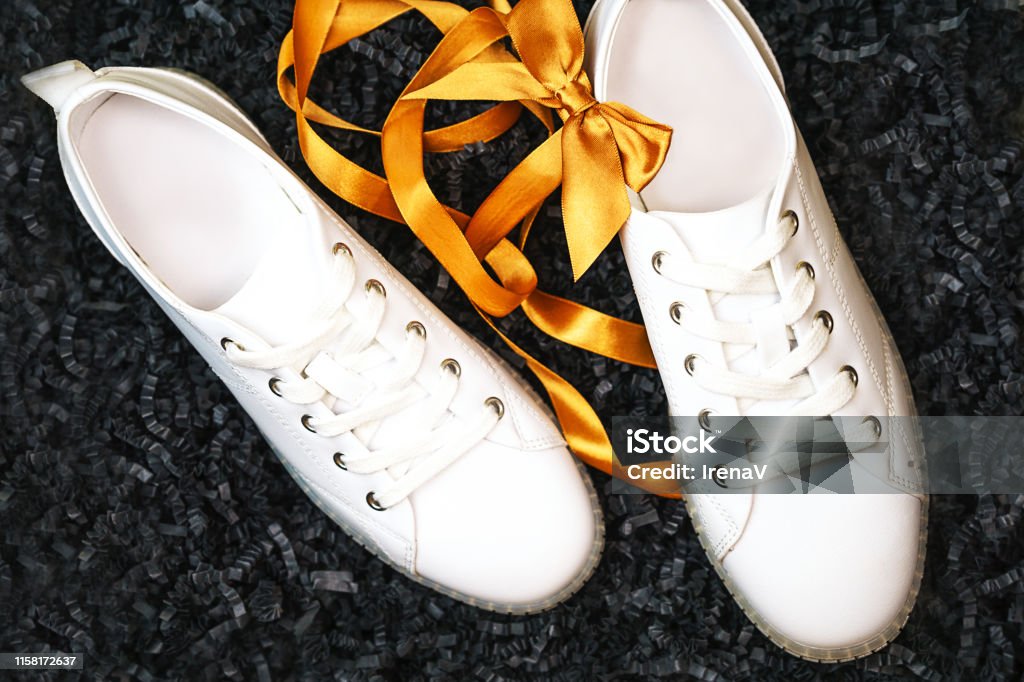 Las Zapatillas Blancas Y El Lazo Amarillo Sobre El Fondo Negro Texturizado Foto de y más banco de imágenes de A la moda - iStock