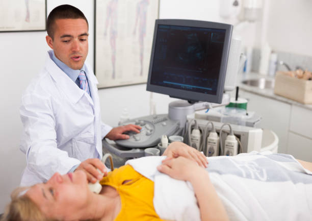 istock Woman undergoing examination thyroid lying by man doctor with ultrasonic device 1158173449