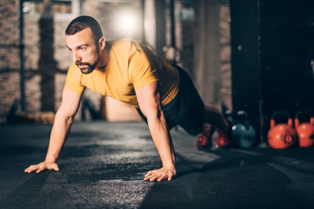 istock Young male athlete doing push ups workout in a gym 1158175130
