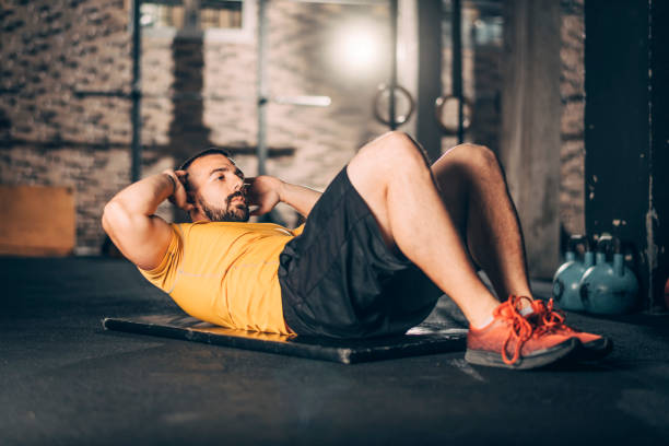 istock Young muscular athlete doing a sit ups workout in a gym 1158175186