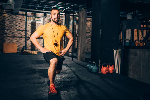 istock Muscular sporty young man doing a lunge exercise in a gym 1158176097