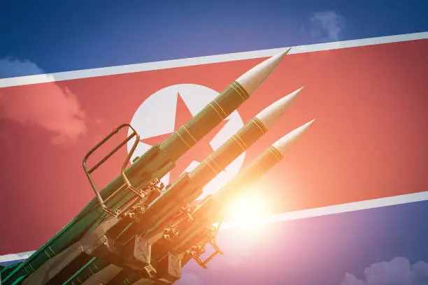 Ballistic missiles or rockets at North Korea flag background. Weapons of mass destruction and threat of nuclear war concept