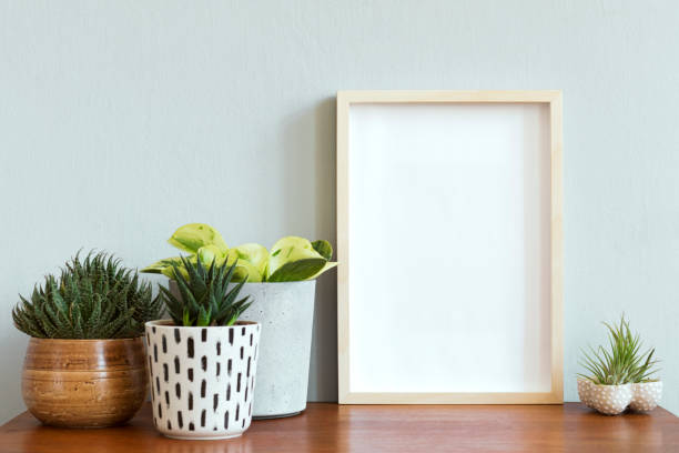 istock Stylish scandinavian interior with design retro table, white mock up photo frame and beautiful plants in design pots and accessories. Modern home decor. Gray background wall. Minimalistic concept. 1158179095