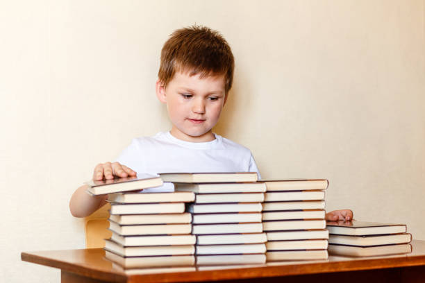 istock a diligent boy sits at a Desk and puts books on stacks. 1158179371