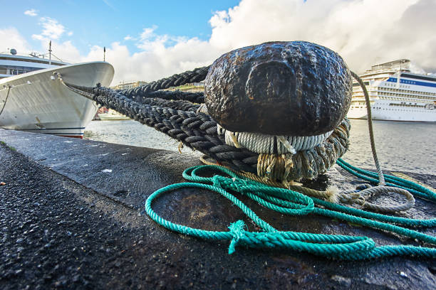 Rope Close-up of a bollard with rope and ship. mooring line stock pictures, royalty-free photos & images