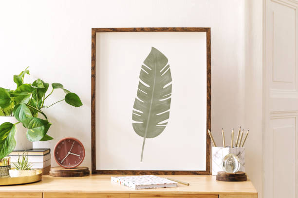 istock Modern scanidnavian interior with mock up photo frame, design office accessories and plants on the wooden desk. Beautiful mirror on the white wall. Creative desk of home decor. Warm and sunny room. 1158180215