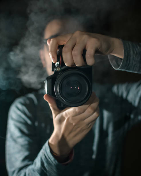 istock Professional photographer with a camera. Black background. 1158182510