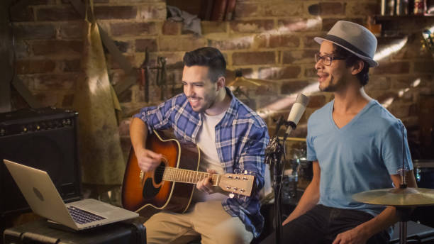 istock Two young man sing and play guitar while recording a song in a home studio in a garage. 1158183691