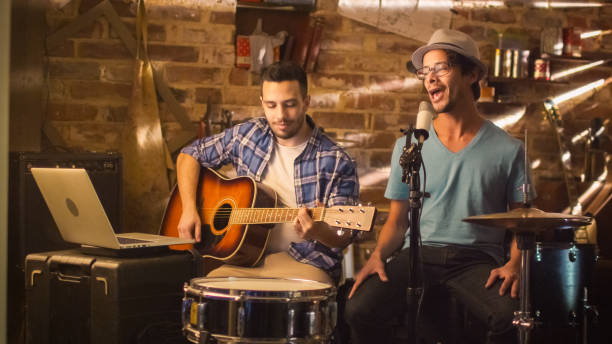 istock Two young man sing and play guitar while recording a song in a home studio in a garage. 1158183700