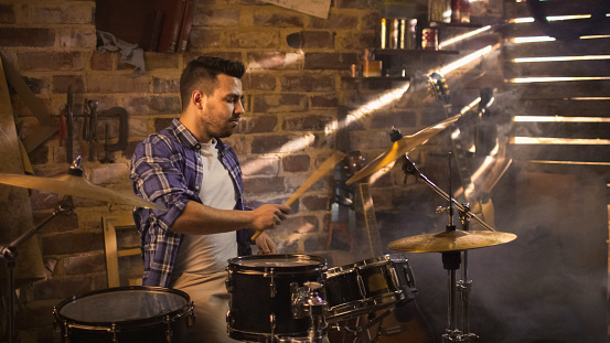 Drummer toca música mientras ensaya una canción en un estudio casero en un garaje. photo