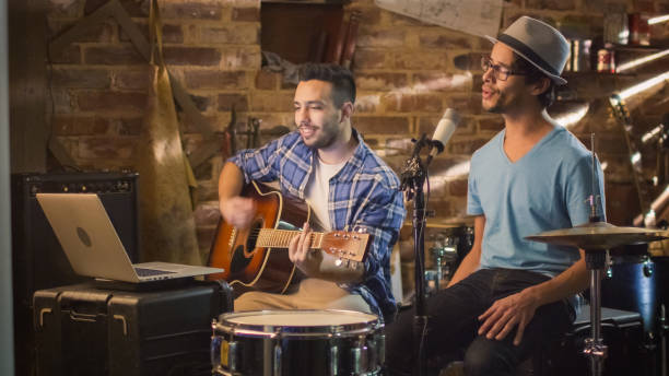 istock Two young man sing and play guitar while recording a song in a home studio in a garage. 1158183764