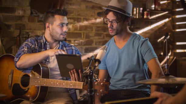 istock Band of musicians have a discussion in a garage studio while using a tablet computer. 1158183766