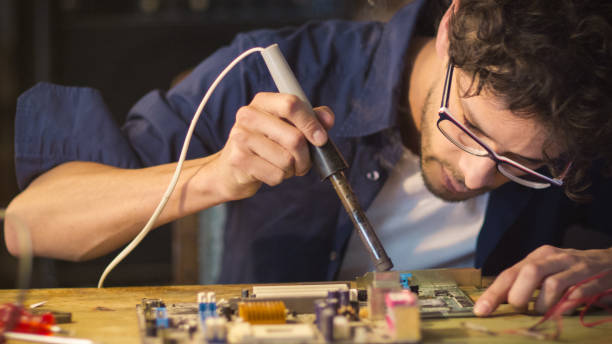 istock Student is studying electronics and soldering a circuit board in a garage. 1158183781