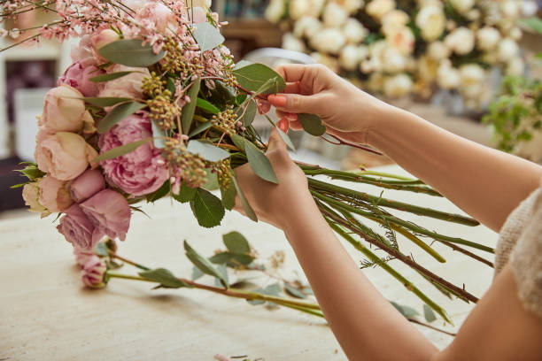 florist making bouquet of roses and peonies at workspace stock photo