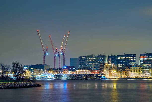 View of modern buildings and cranes at night in Amsterdam
