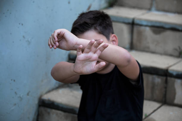 한 어린 소년이 손바닥으로 자신을 보호하고 얼굴을 가린다. 소년 폭력을 남용하지 말하십시오. 폭력, 두려움, 두려운 아이 - child abuse child fear depression 뉴스 사진 이미지