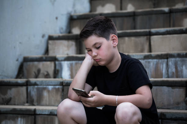 istock Sad Boy Looking At Mobile Phone With Hand On Head 1158186843