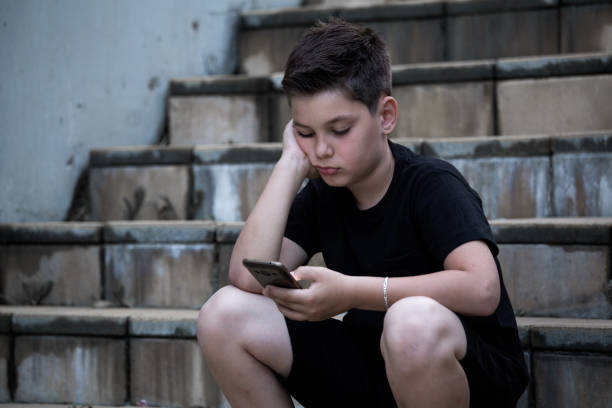 istock Sad Boy Looking At Mobile Phone With Hand On Head 1158186846