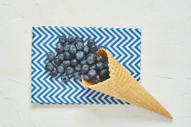 istock Top view of waffle cone with blueberries on blue textile 1158189911