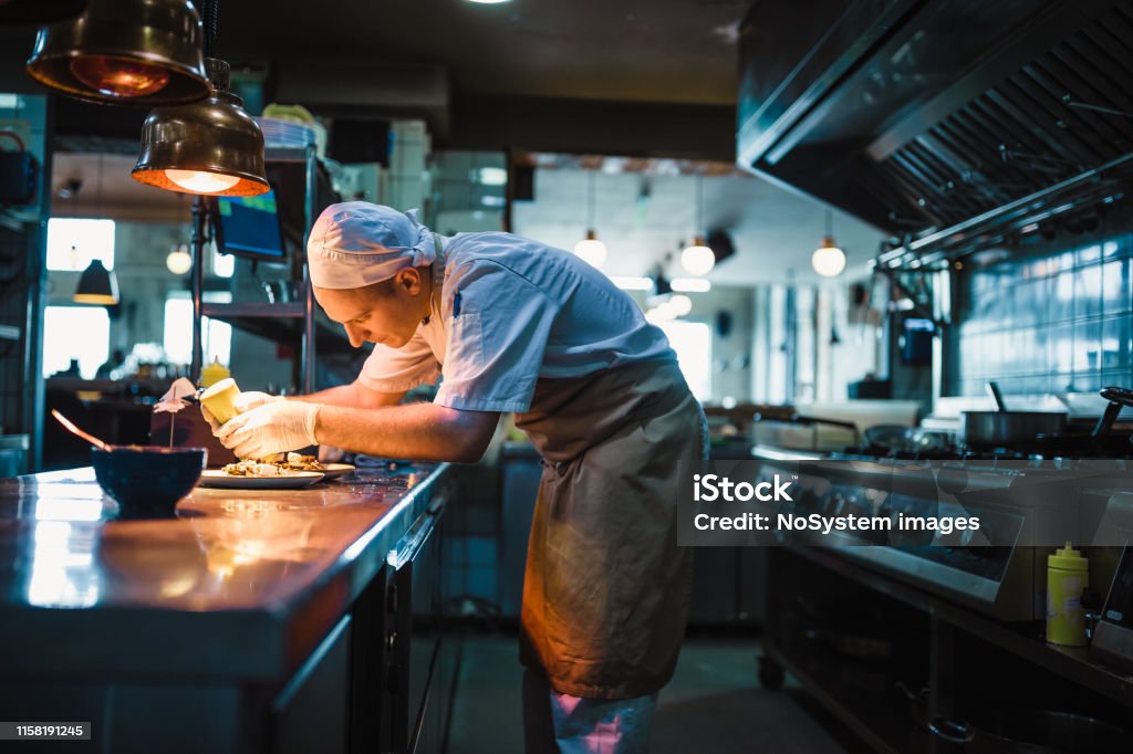 Chef serving food Chef serving food in the modern kitchen in a high-end restaurant Chef Stock Photo