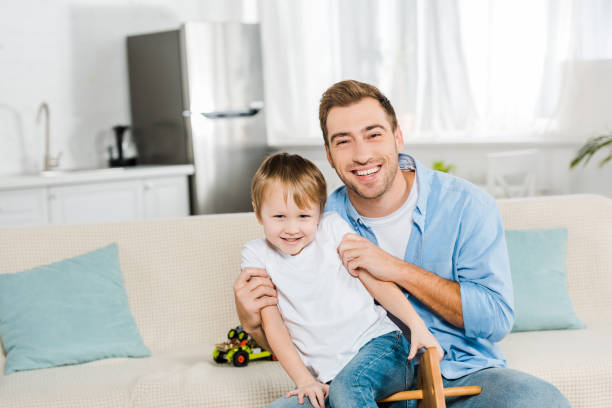 istock happy father hugging son and looking at camera at home 1158192923