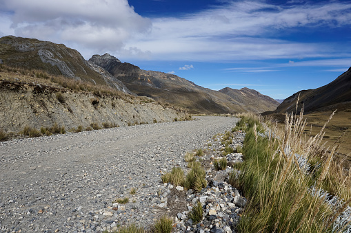 gravel road cutting through empty high alpine grasslands in the Andes of Peru in the middle of nowhere