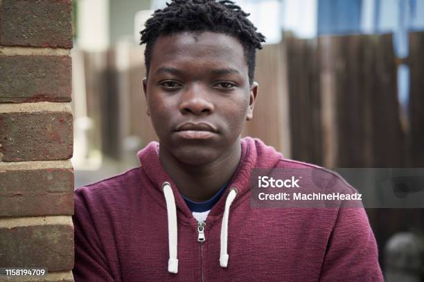 Portrait Of Serious Teenage Boy Leaning Against Wall In Urban Setting Stock Photo - Download Image Now