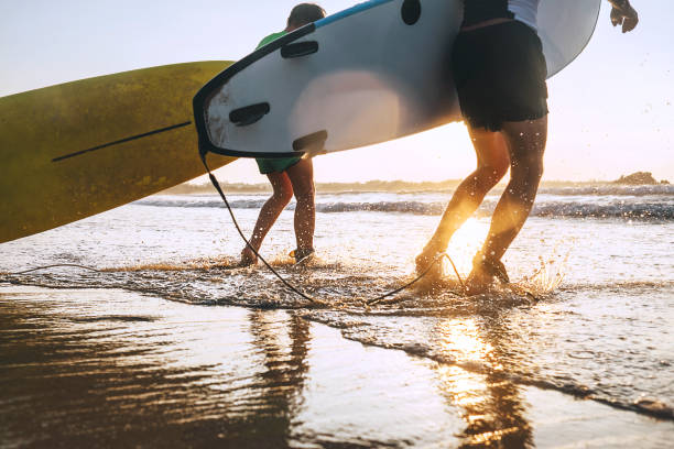 istock Son and father surfers run in ocean waves with surfing boards 1158194731