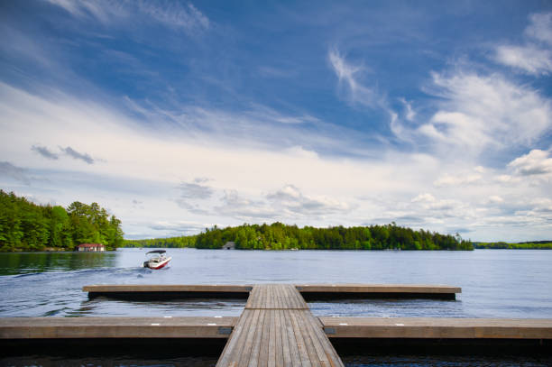 istock Cottage lake view with a motorboat leaving the dock 1158195501