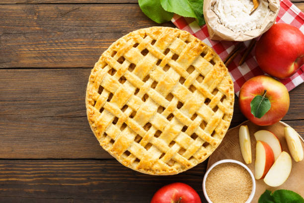 istock Apple pie with lattice top and ingredients on wooden table. 1158200298