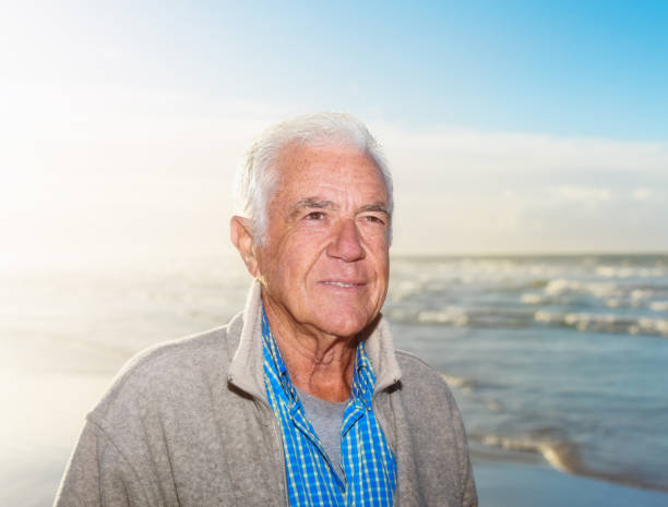 istock Handsome senior man walking on the beach 1158204301