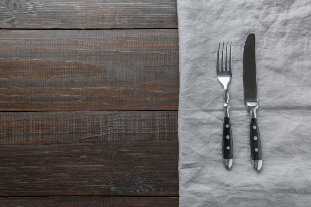 istock Rustic black silverware with napkin on old brown wooden board. Top view with copy space for your menu or recipe. 1158209063