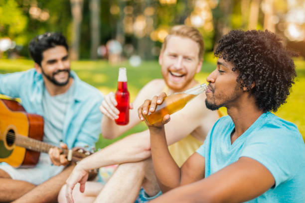 três homens novos que bebem e que têm o divertimento em um festival da música. - music festival park friendship summer - fotografias e filmes do acervo