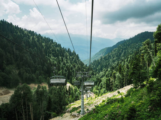 Chairlifts at mountains and forest background at cloudy summer day