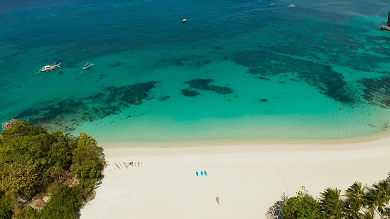 Tropical white sand beach in a lagoon with turquoise water on Boracay Island, Philippines, aerial view. Seascape with beach on tropical island. Summer and travel vacation concept.