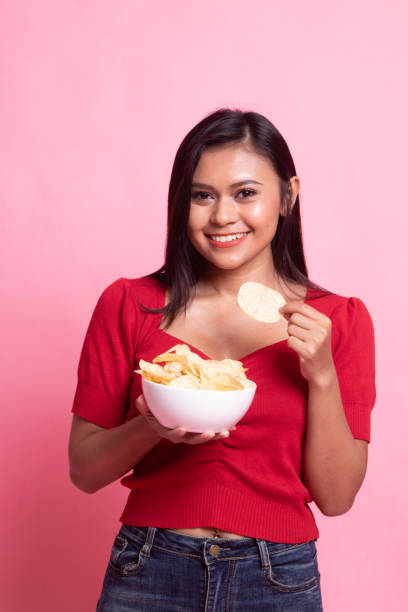 istock Young Asian woman eat potato chips. 1158218682
