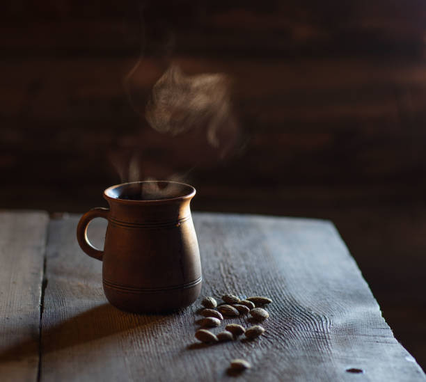 hot coffee in a stein with steam on a wooden board. country style. almond kernel