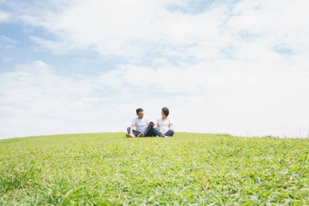 istock Asian couple with dog relaxed on grass under blue sky 1158220024