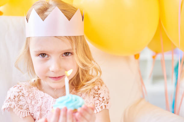 istock Cute girl holding cupcake with candle 1158220695