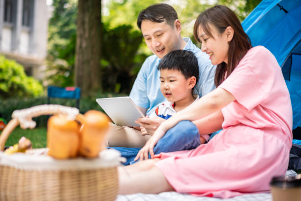 istock Asian family using a digital tablet when camping in forest park 1158224485