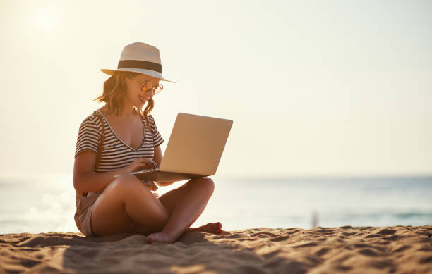 joven que trabaja con la computadora portátil en la naturaleza en la playa - travel red vacations outdoors fotografías e imágenes de stock