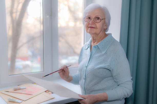 An elderly woman is going to draw stock photo