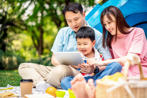 istock Asian family using a digital tablet when camping in forest park 1158225602
