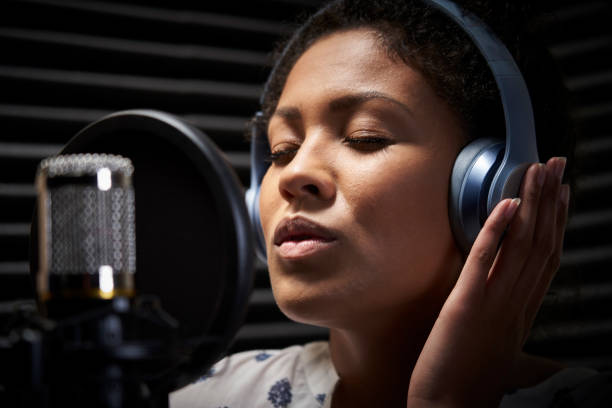 chanteur féminin utilisant des écouteurs chantant dans le microphone dans le studio d'enregistrement - singer singing women microphone photos et images de collection