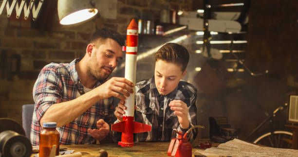 Father and son are modeling a toy rocket in a garage at home. Father and son are modeling a toy rocket in a garage at home. model rocket stock pictures, royalty-free photos & images